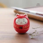 Daruma chat en céramique colorée, symbole de chance